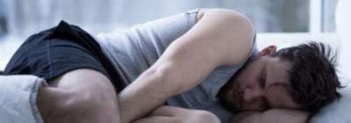 Man experiencing restless legs syndrome symptoms at night
